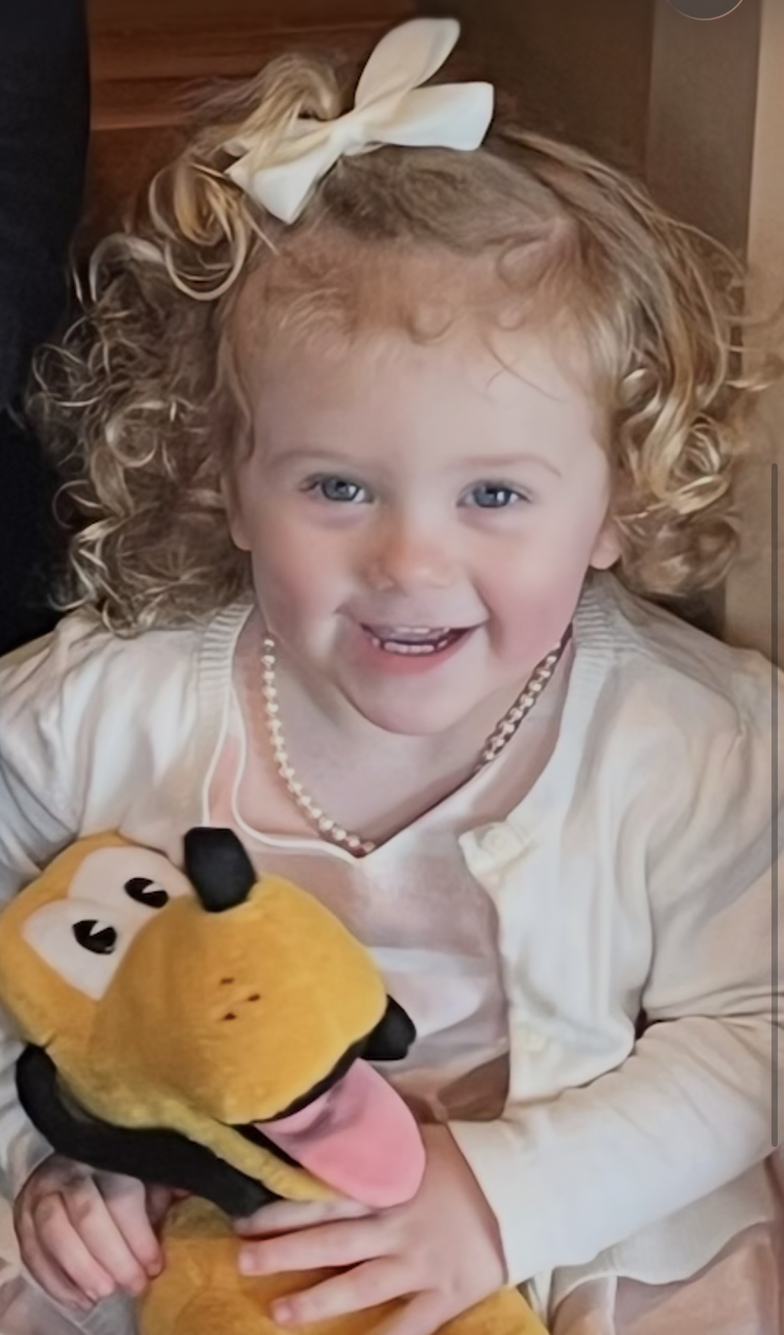 Norah smiling and happy, holding her Pluto stuffed animal